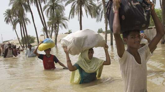 Menschen waten mit Hab und Gut durch Wasser