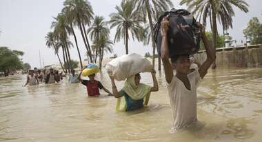 Menschen waten mit Hab und Gut durch Wasser
