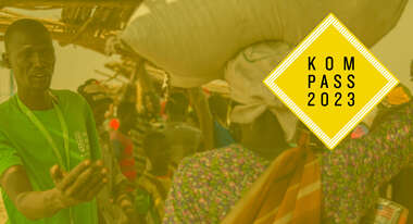 Ein Mann in Welthungerhilfe-T-Shirt verteilt Hilfsgüter in Bentiu, Südsudan. Oben rechts ist das Logo des Kompass 2023 eingeblendet.