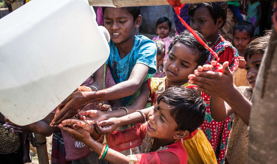 Kinder waschen sich an einer Wasch-Vorrichtung die Hände.