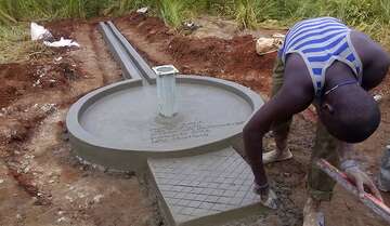 Ein Mann verputzt einen neu entstandenen Brunnen