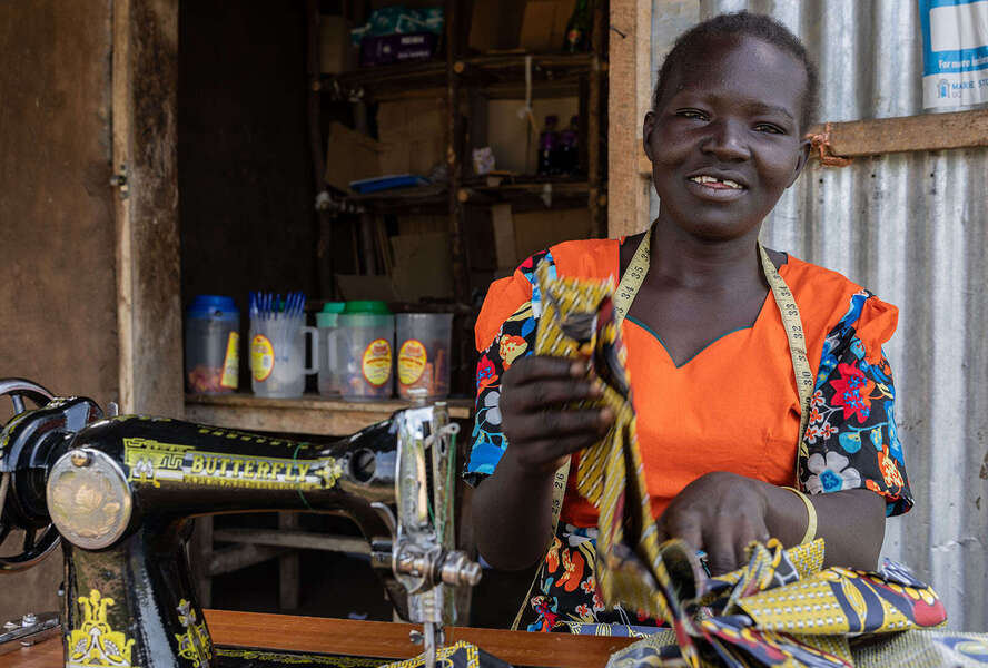 Frau sitzt lächelnd an ihrer Nähmaschine