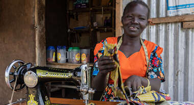 Frau sitzt lächelnd an ihrer Nähmaschine