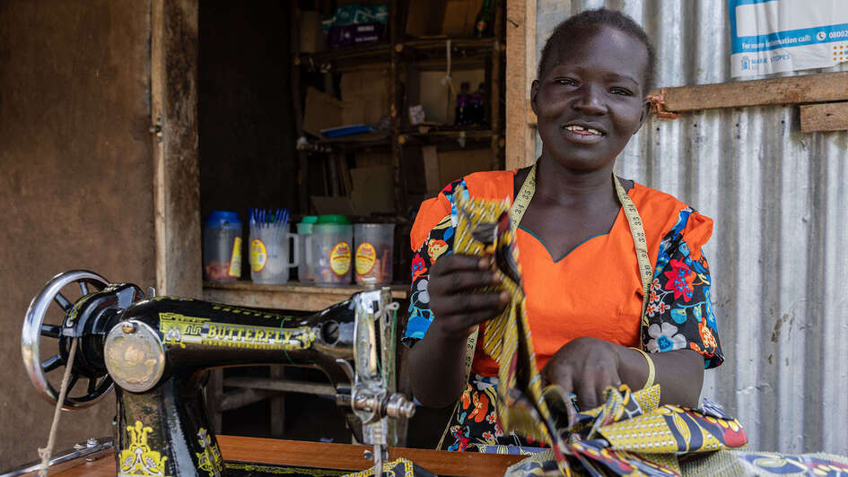 Frau sitzt lächelnd an ihrer Nähmaschine