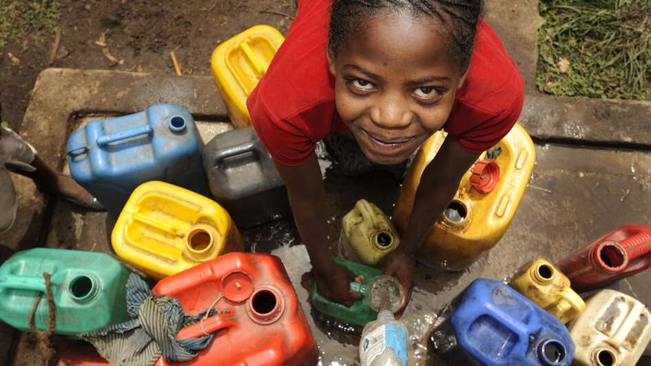 Mädchen am Brunnen mit Wasserkanistern
