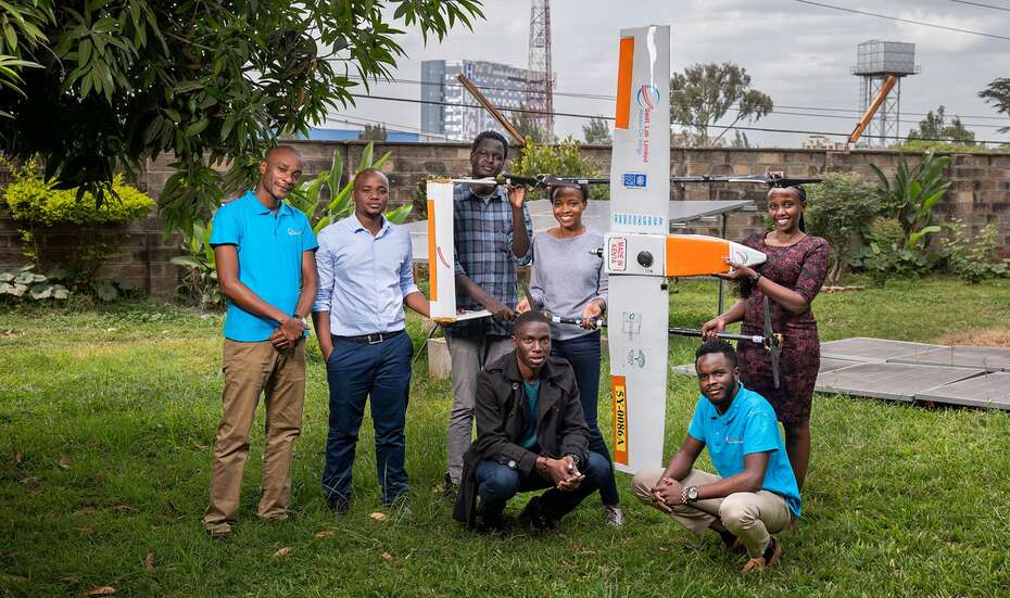 Team von Swift Lab: Sieben junge Leute lächeln in die Kamera und halten ein Flugobjekt mit Drohne.