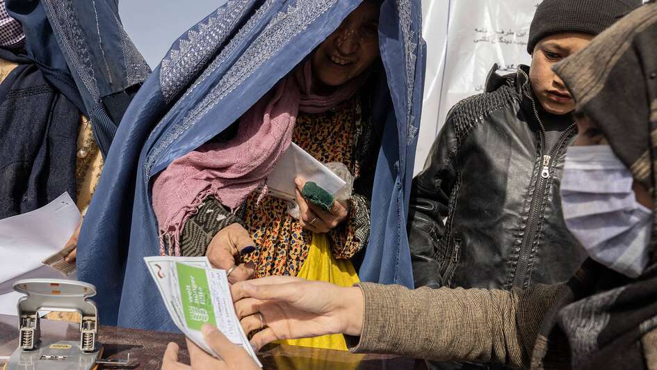 Eine Frau lächelt und nimmt ein Registrierungsausweis entgegen.