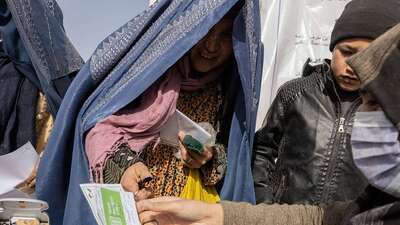 Eine Frau lächelt und nimmt ein Registrierungsausweis entgegen.