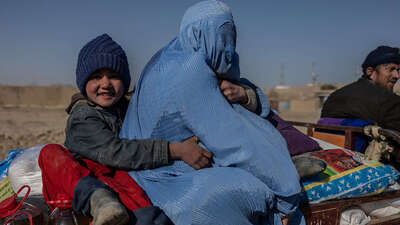 Ein Mädchen sitzt mit ihrer Mutter auf der Ladefläche eines Wagens, Afghanistan 2022.
