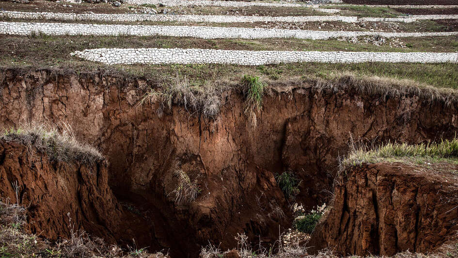 Ein kraterartiges Loch in der Erde. Im Hintergrund sieht man weiße Schutzwälle.