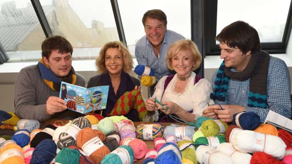 Mehrere Personen, darunter Michaela May, häkeln.