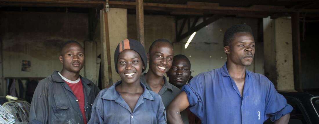 Jetzt als Unternehmen helfen. Bildbeschreibung: Eine Gruppe Jugendlicher in einer Autowerkstatt.