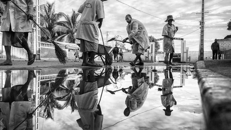 Vier Straßenfeger putzen die Straße 