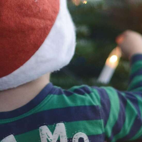 Anlassspende zu Weihnachten: Zwei Kinder mit Weihnachtsmützen vor dem Tannenbaum