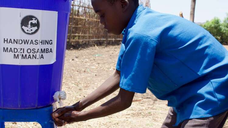 Ein Kind wäscht sich die Hände an einer malawischen Grundschule.