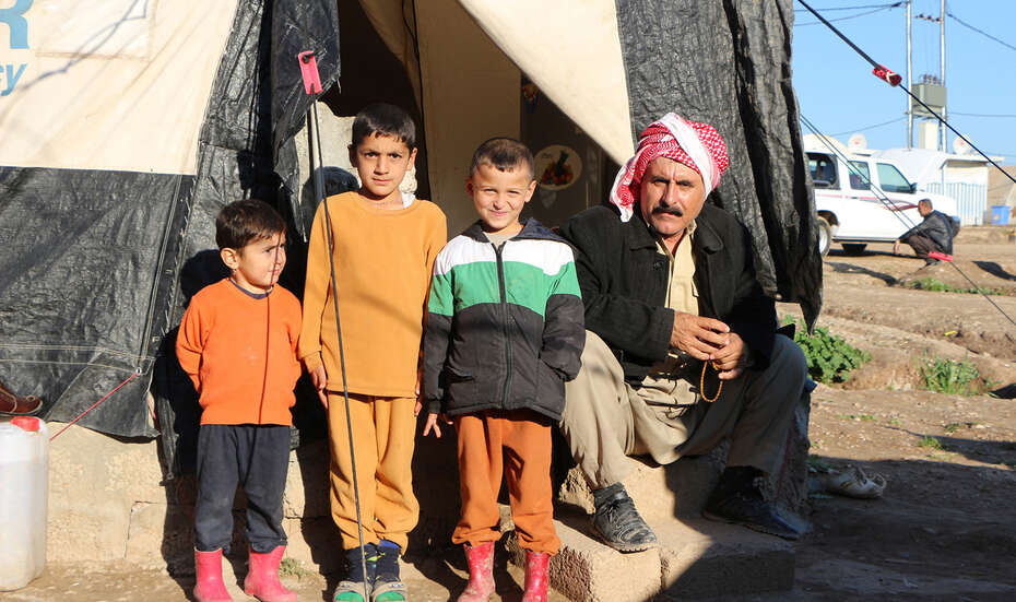 Familie sitzt vor ihrem Zelt