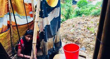 Eine Frau sitzt auf dem Boden, ihre Hände sind voller Asche.