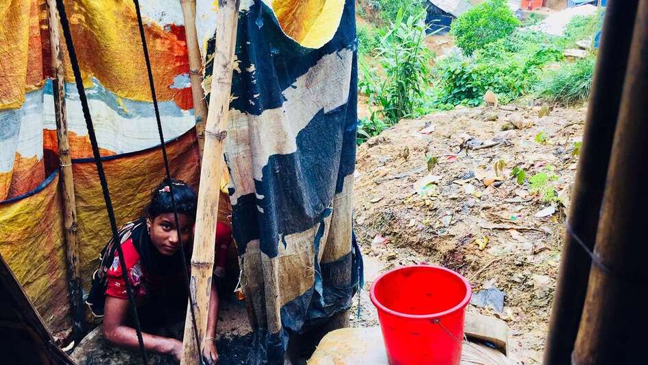 Eine Frau sitzt auf dem Boden, ihre Hände sind voller Asche.