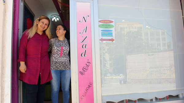 Zwei Frauen stehen lächelnd im Eingang eines Ladens.