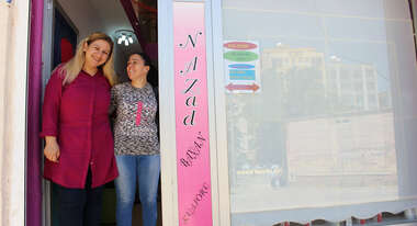 Zwei Frauen stehen lächelnd im Eingang eines Ladens.