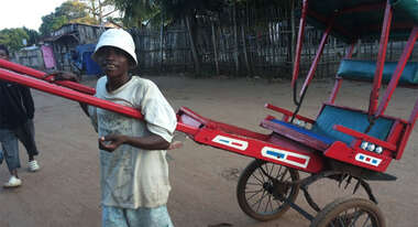 Ein Junge zieht ein Pousse-Pousse (Ein Riksha-ähnliches Taxi)