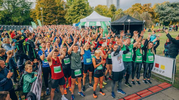 Eine große Menge an Läufer*innen steht an der Startlinie eines Spendenlaufs und hält die Hände in die Höhe.