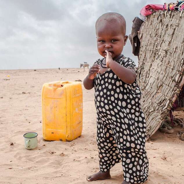 Ein Kleinkind steht vor einem Zelt in der Wüste während einer extremen Dürreperiode, Somaliland 2017. 