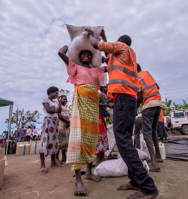 Eine Frau bekommt von einem Mann in Sicherheitsweste Säcke und Pakete.