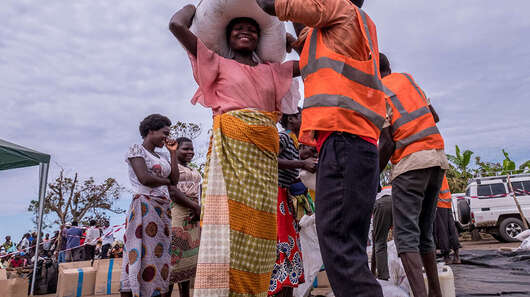 Eine Frau bekommt von einem Mann in Sicherheitsweste Säcke und Pakete.