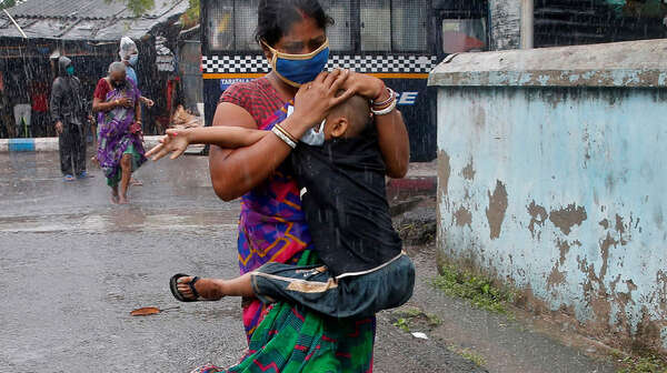 Eine Frau mit Mundschutz trägt ein Kind auf dem Arm.