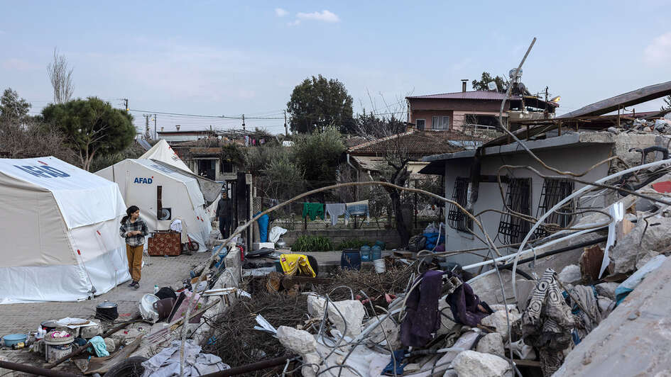 Ein altes und durchs Erdbeben zerstörtes Haus steht neben neu aufgebauten Zelten.