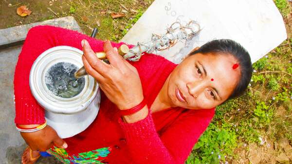 Frau füllt Wasser in einen Krug