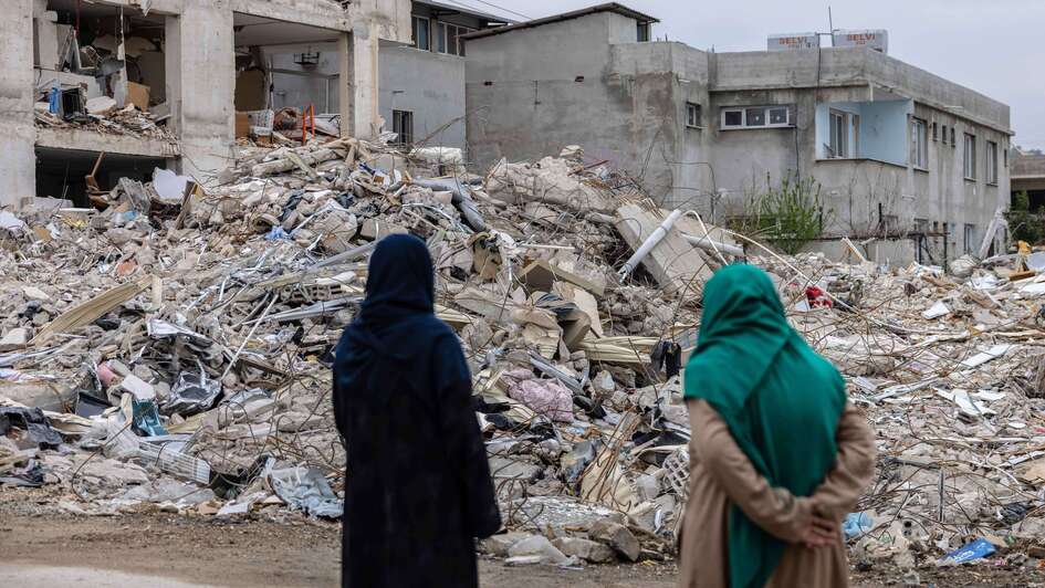 Nach dem Erdbeben in der Türkei: Zwei Frauen stehen vor den Trümmern eingestürzter Gebäude