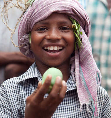 Der achtjährige Jalia Pacharia hält sein Lieblingsessen in die Höhe: einer wilde Gurke. Die Paharia im indischen Dorf Ketokuria sammeln seit jeher Dutzende Sorten wilder Waldgewaechse wie Knollen, Wurzeln, Früchte und Gemüse, doch durch Waldrodungen, finden sie immer weniger Essbares. Der Welthungerhilfe-Partner CWS/Avibyakti Foundation hilft ihnen, die Vielfalt zu erhalten. 