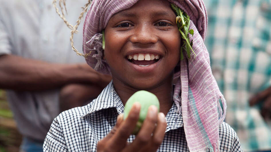 Der achtjährige Jalia Pacharia hält sein Lieblingsessen in die Höhe: einer wilde Gurke. Die Paharia im indischen Dorf Ketokuria sammeln seit jeher Dutzende Sorten wilder Waldgewaechse wie Knollen, Wurzeln, Früchte und Gemüse, doch durch Waldrodungen, finden sie immer weniger Essbares. Der Welthungerhilfe-Partner CWS/Avibyakti Foundation hilft ihnen, die Vielfalt zu erhalten. 