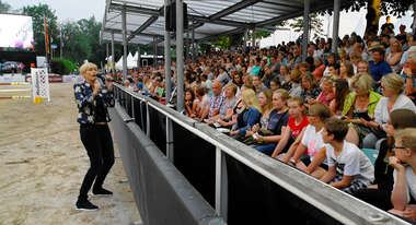Die Schauspielerin Gesine Cukrowski steht auf einem Reitplatz und moderiert die SMS-Spendenaktion vor vielen Zuschauern.