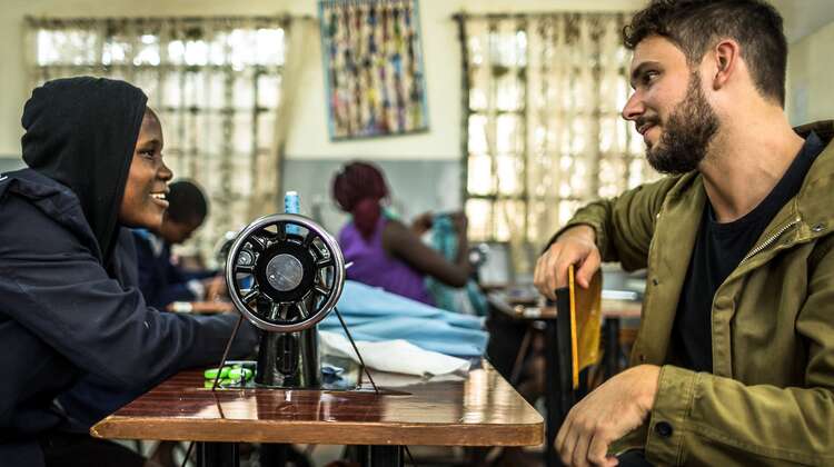 Robert Redweik mit einer Frau vor einer Nähmaschine während eines Besuchs des "Skill up!"-Projekts in Nairobi, Kenia.