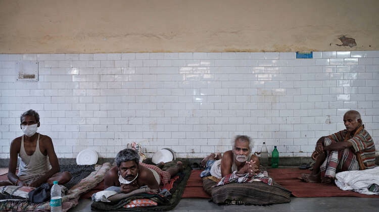 Männer liegen auf Matratzen und schauen in die Kamera.