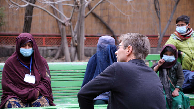 2022-afghanistan-hires-frauen-gespraech-mathias-mogge_C_parwiz-sabawoon-welthungerhilfe.jpg Verschleierte Frauen im Gespräch mit Welthungerhilfe Generalsekretär Mathias Mogge. Sie alle sitzen auf Bänken.