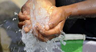 Kind schöpft Wasser mit den Händen