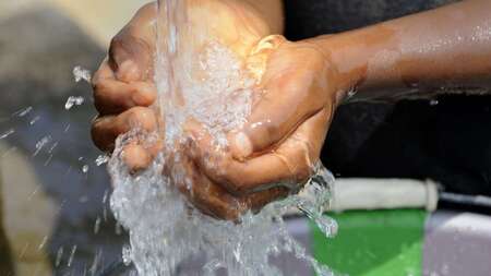 Kind schöpft Wasser mit den Händen