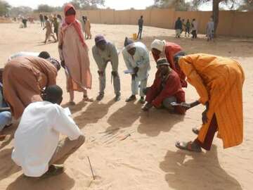 Mehrere Männer stehen und sitzen in einem Kreis.