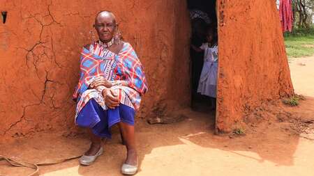 Massai Esther Sululi Makooi vor einer Hütte.