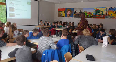 Schulklasse schaut sich etwas an einer Leinwand an.