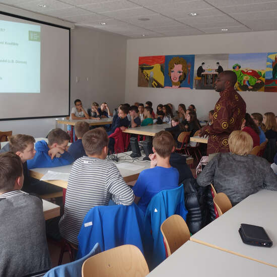 Schulklasse schaut sich etwas an einer Leinwand an.