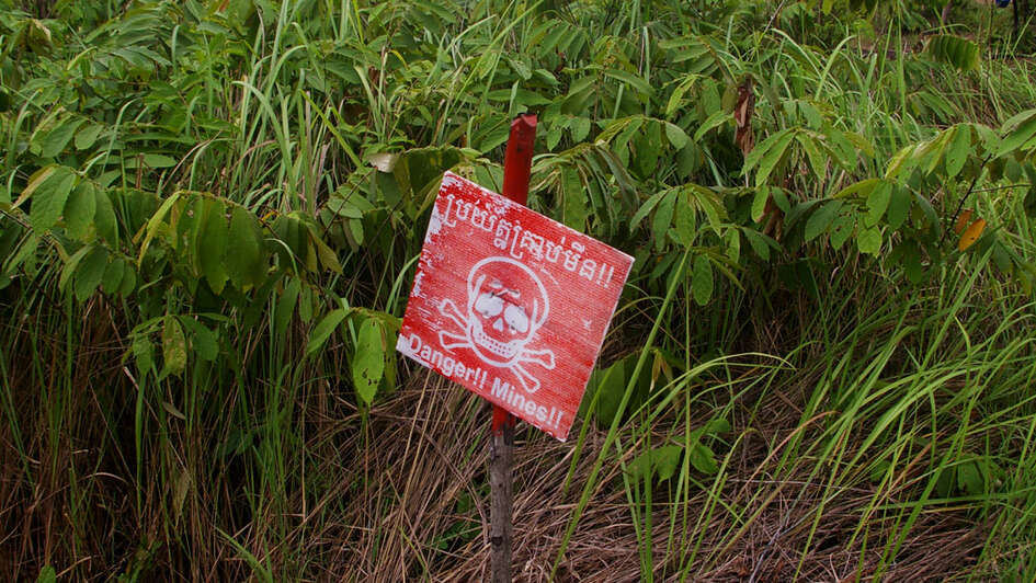 Ein rotes Schild mit einem Totenkopf darauf warnt vor Minen