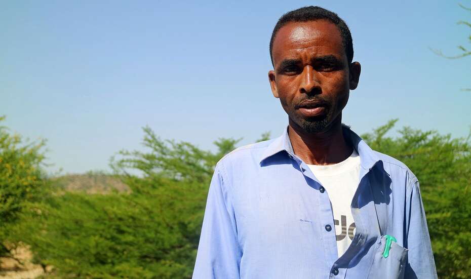 Ein Kleinbauer mit blauem Hemd schaut in die Kamera.