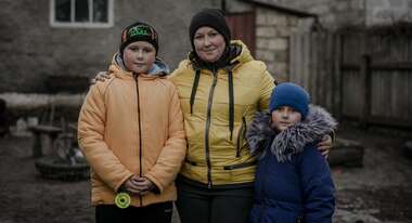 Eine Mutter und ihre beiden Kinder lächeln in die Kamera für eine Profilaufnahme