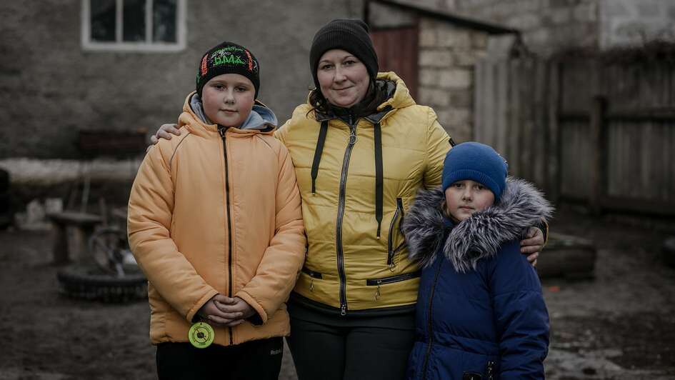 Eine Mutter und ihre beiden Kinder lächeln in die Kamera für eine Profilaufnahme