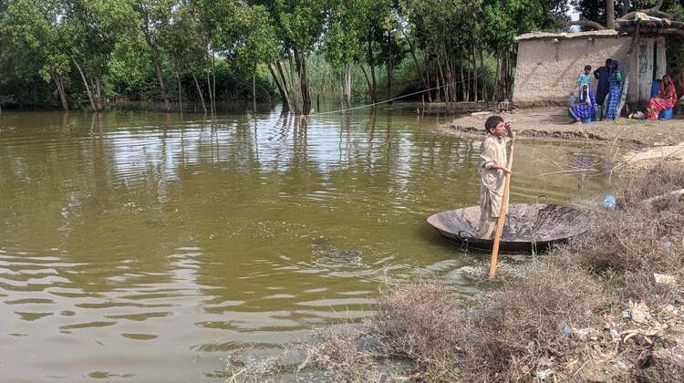 Ein Junge steht auf einer großen Pfanne und schwimmt damit über die überschwemmten Bereiche.